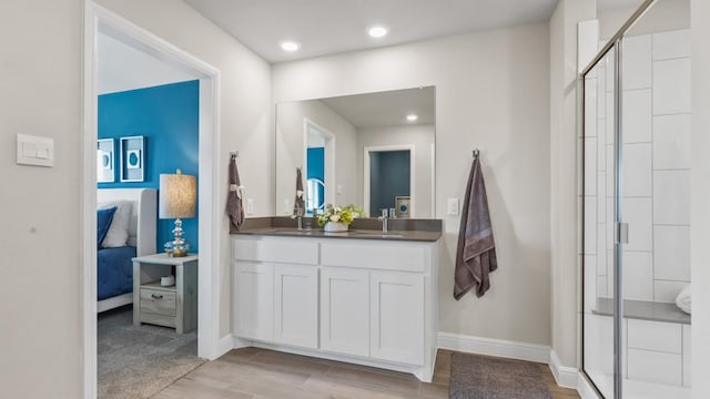ensuite bathroom featuring a sink, ensuite bathroom, a stall shower, baseboards, and wood finished floors