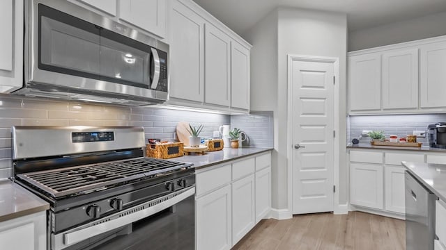 kitchen featuring white cabinetry, tasteful backsplash, appliances with stainless steel finishes, light countertops, and light wood-type flooring