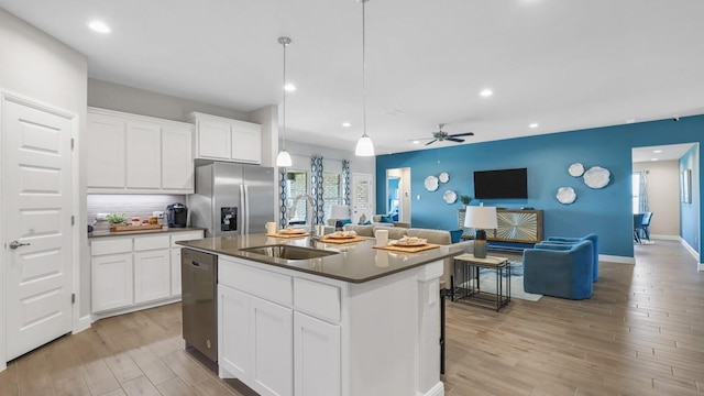 kitchen with a sink, appliances with stainless steel finishes, open floor plan, light wood-type flooring, and recessed lighting