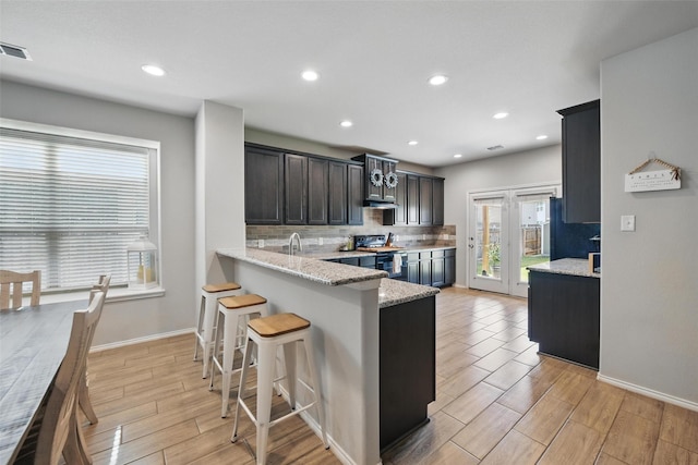 6309 Outrigger Rd, Fort Worth, TX 76179 - kitchen with electric range, tasteful backsplash, a breakfast bar area, light stone countertops, and baseboards