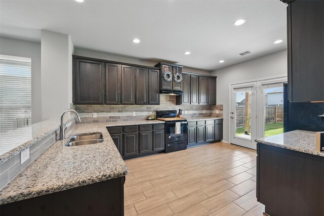 6309 Outrigger Rd, Fort Worth, TX 76179 - kitchen with black electric range, a sink, light stone countertops, backsplash, and recessed lighting