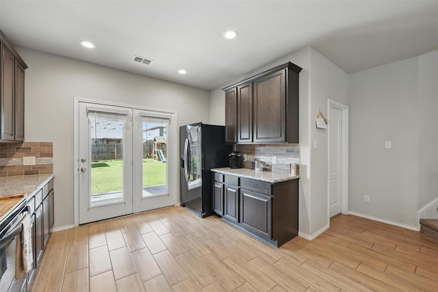 6309 Outrigger Rd, Fort Worth, TX 76179 - kitchen with black fridge, tasteful backsplash, dark brown cabinets, light wood-type flooring, and recessed lighting