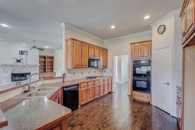 kitchen with a sink, ceiling fan, black appliances, a peninsula, and a stone fireplace