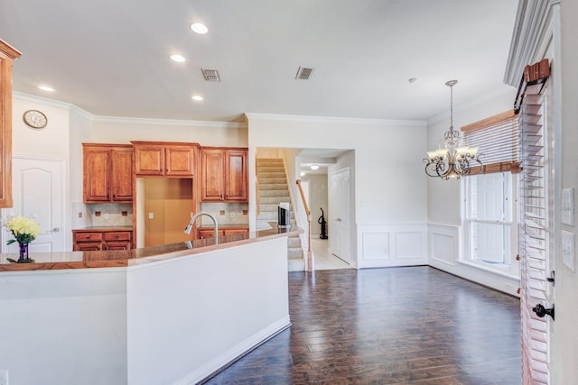 kitchen featuring dark wood-style flooring, brown cabinetry, crown molding, visible vents, and backsplash