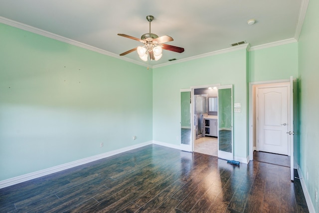 spare room with crown molding, visible vents, ceiling fan, baseboards, and wood finished floors