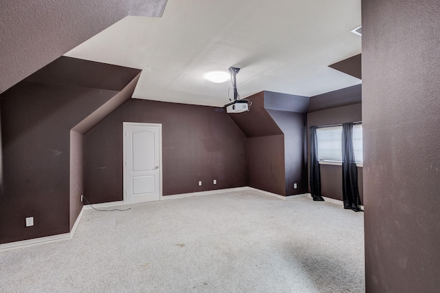 additional living space featuring vaulted ceiling, carpet, and baseboards