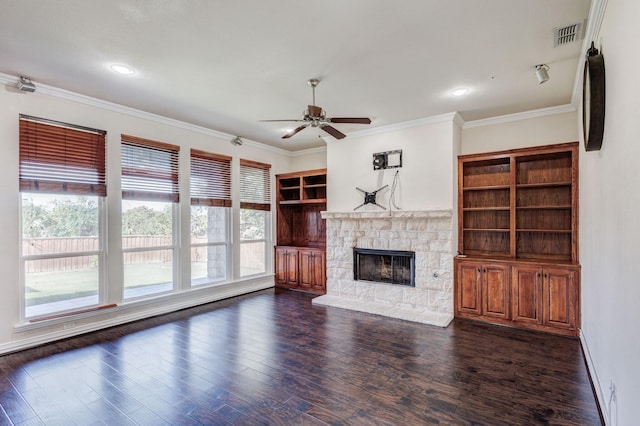 unfurnished living room featuring crown molding, ceiling fan, a stone fireplace, and wood finished floors