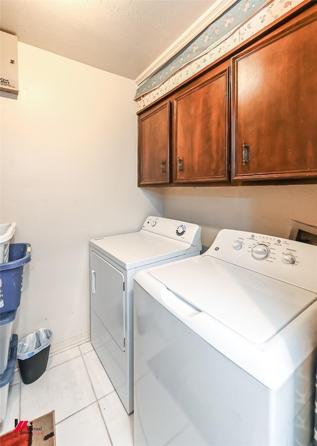 laundry area with light tile patterned flooring, cabinet space, and washing machine and clothes dryer
