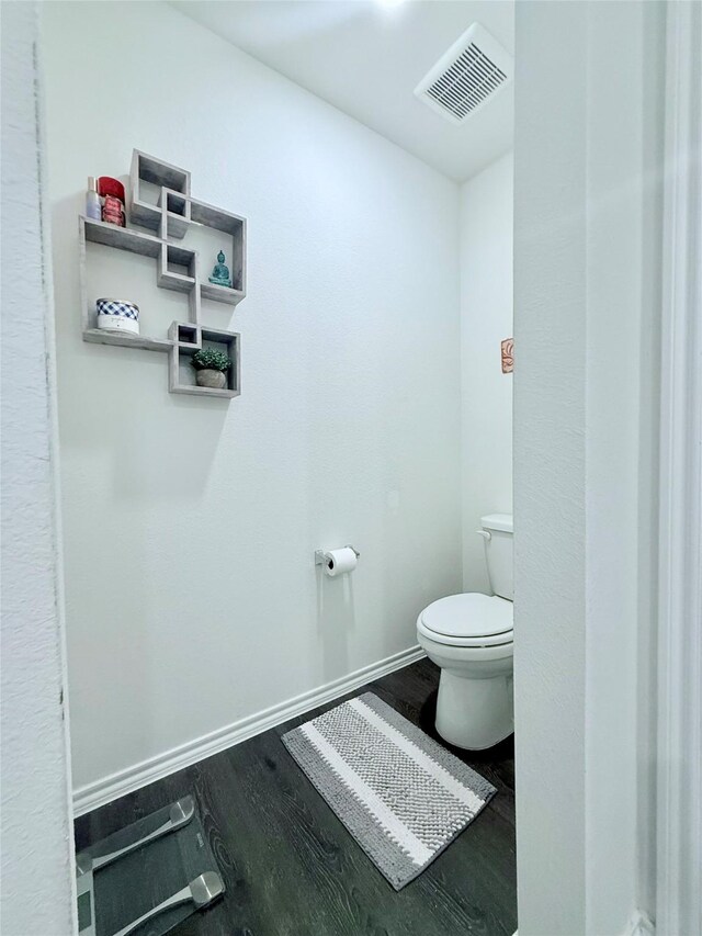 bathroom featuring visible vents, baseboards, wood finished floors, and toilet