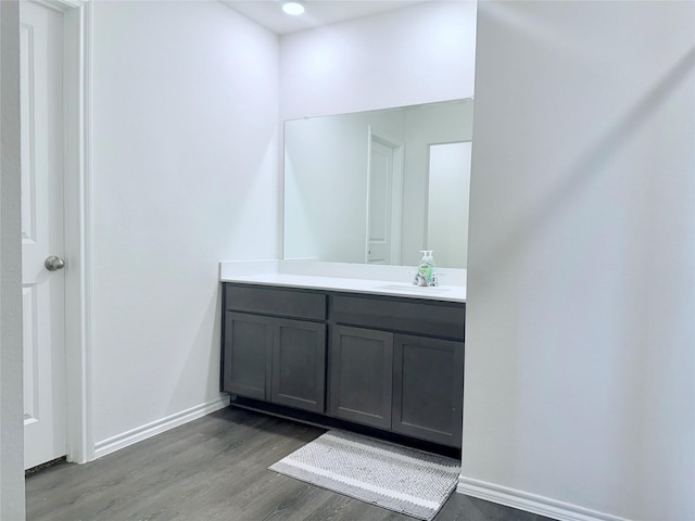 bathroom with baseboards, vanity, and wood finished floors
