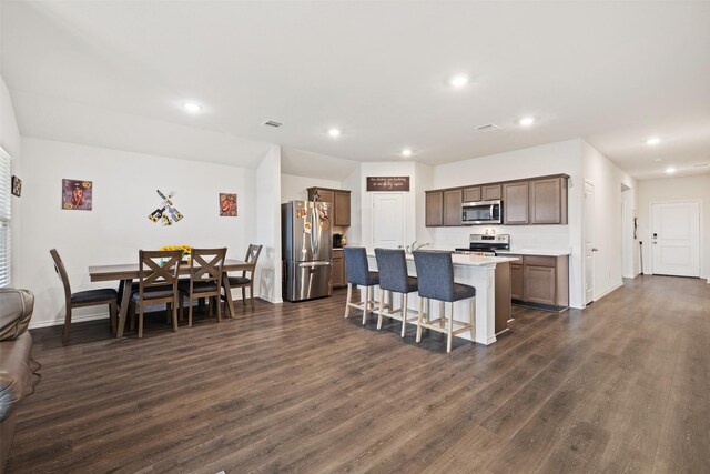 2802 Elk Rd, Crandall, TX 75114 - kitchen with appliances with stainless steel finishes, dark wood finished floors, a kitchen breakfast bar, a center island with sink, and light countertops