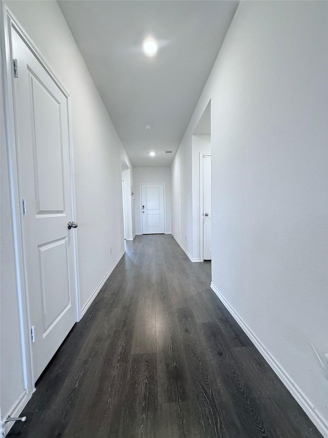 hall featuring baseboards and dark wood-type flooring