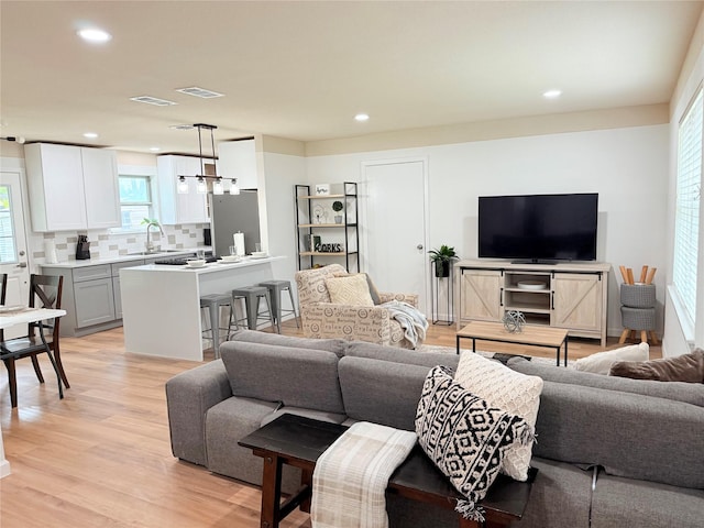 living area featuring visible vents, light wood-type flooring, and recessed lighting