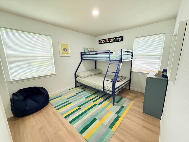 bedroom featuring light wood finished floors and baseboards