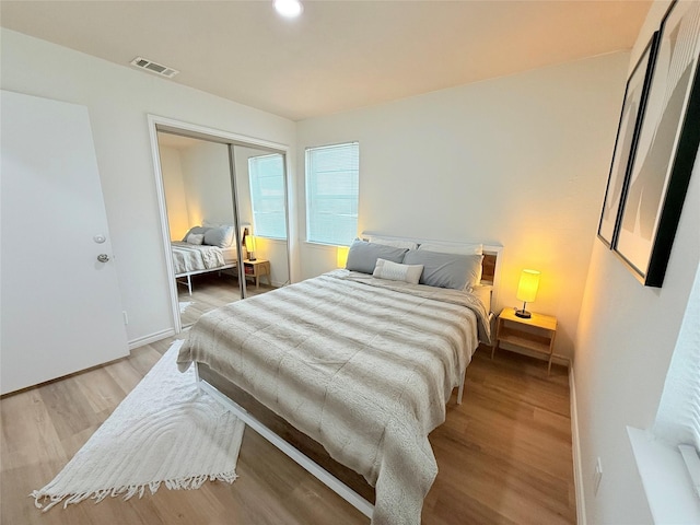 bedroom featuring a closet, visible vents, light wood-style flooring, and baseboards