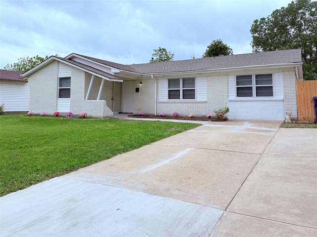ranch-style house with a shingled roof, brick siding, a front lawn, and driveway