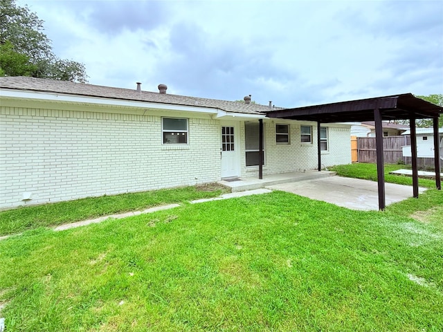 rear view of property featuring fence, a lawn, a patio area, and brick siding