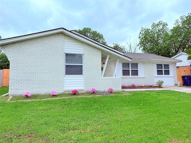 ranch-style home featuring brick siding, fence, and a front lawn