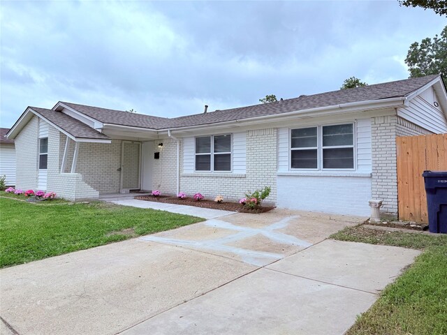single story home with a front lawn, fence, roof with shingles, and brick siding