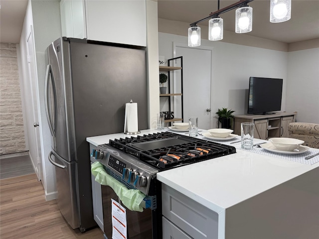 kitchen with hanging light fixtures, stainless steel appliances, light wood-style floors, light countertops, and open floor plan