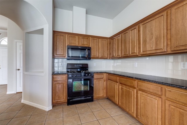 kitchen featuring black range with gas cooktop, arched walkways, tasteful backsplash, brown cabinets, and light tile patterned flooring