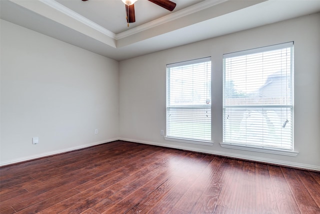empty room with a tray ceiling, ornamental molding, a ceiling fan, and dark wood-type flooring