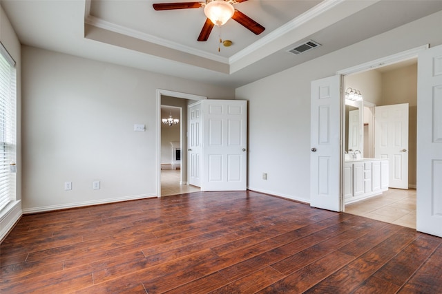 unfurnished bedroom with ornamental molding, a tray ceiling, and light wood-style flooring