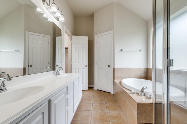 bathroom featuring double vanity, tile patterned floors, a sink, and a garden tub