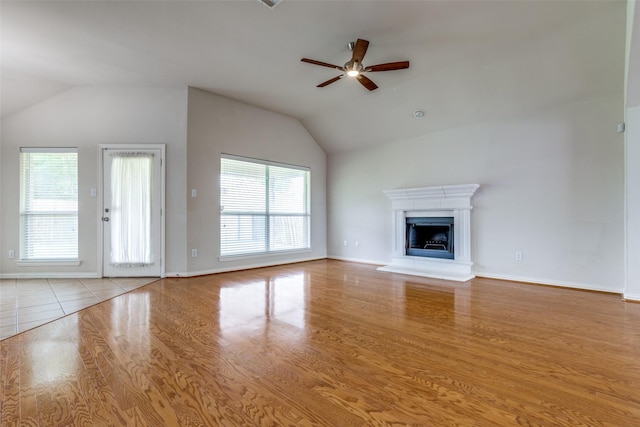 unfurnished living room with plenty of natural light, a ceiling fan, vaulted ceiling, and wood finished floors