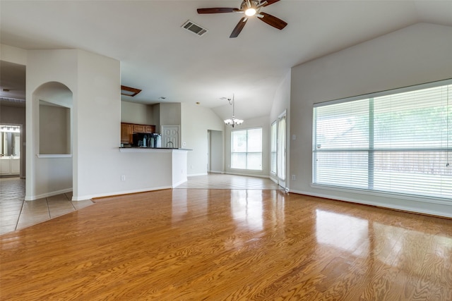 unfurnished living room with visible vents, lofted ceiling, baseboards, light wood finished floors, and ceiling fan with notable chandelier