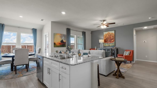 kitchen featuring a sink, a center island with sink, visible vents, dishwasher, and white cabinets