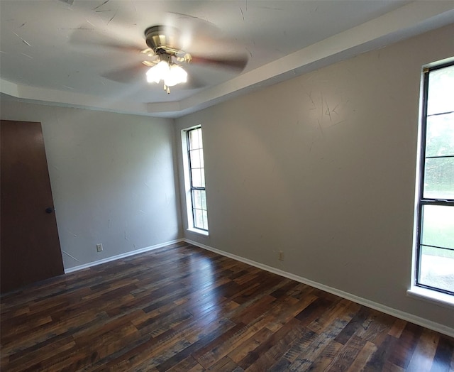 unfurnished room with dark wood finished floors, ceiling fan, and a healthy amount of sunlight