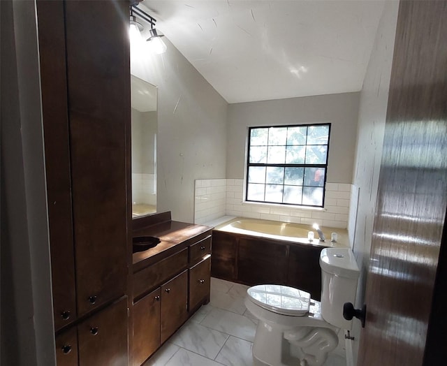 bathroom featuring lofted ceiling, toilet, a bath, vanity, and marble finish floor