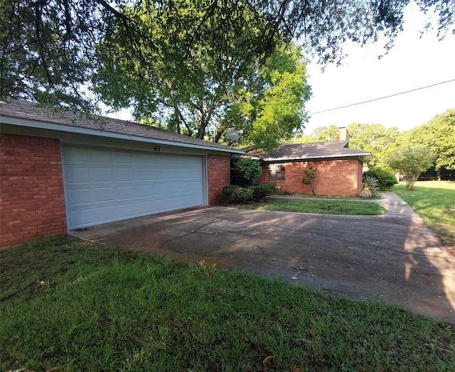 exterior space with a front lawn, a garage, brick siding, driveway, and a chimney