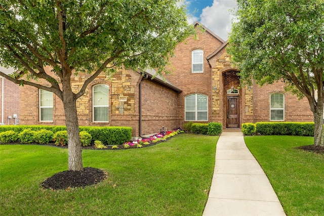 view of front facade with brick siding and a front lawn