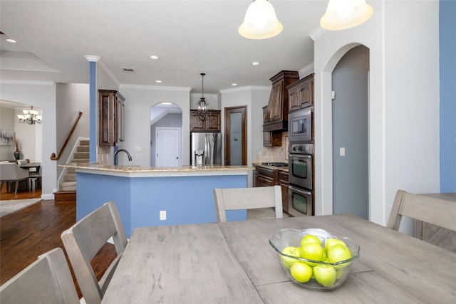 kitchen with a chandelier, stainless steel appliances, visible vents, arched walkways, and dark brown cabinets