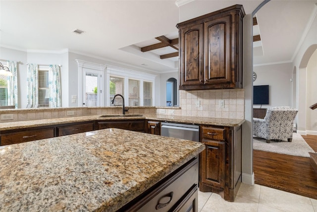 kitchen with a sink, visible vents, light stone counters, ornamental molding, and arched walkways