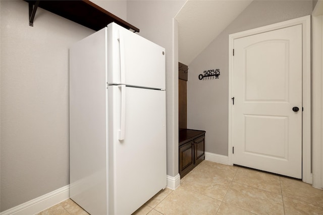 interior space with baseboards, light tile patterned flooring, and vaulted ceiling