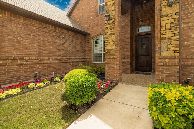 entrance to property featuring brick siding and a shingled roof