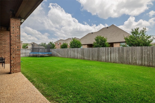 view of yard featuring a trampoline and a fenced backyard