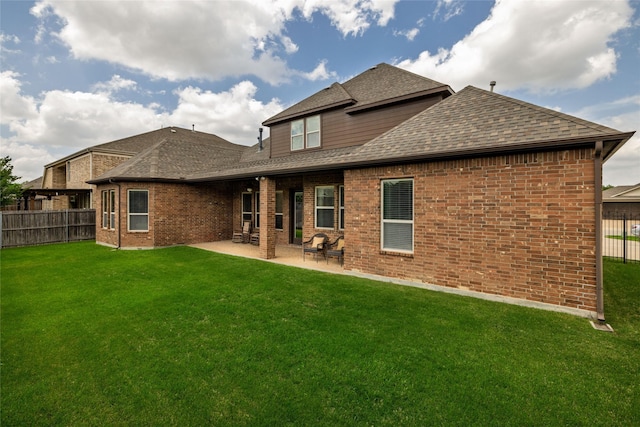 rear view of house with a patio, a shingled roof, a yard, a fenced backyard, and brick siding