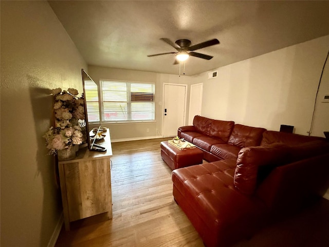 living area featuring a ceiling fan, baseboards, visible vents, and wood finished floors