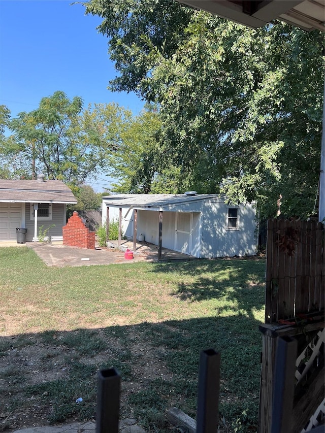 view of yard with a patio, fence, and an outbuilding