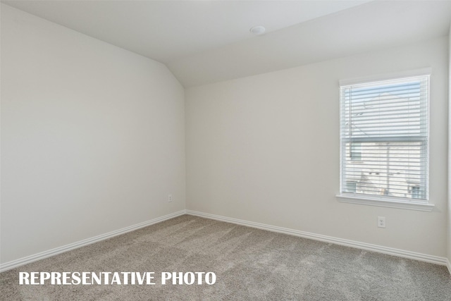 carpeted empty room featuring baseboards and lofted ceiling