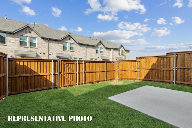 view of yard with a gate, a patio area, a fenced backyard, and a residential view