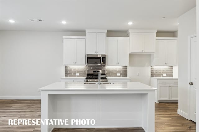 kitchen with a center island with sink, light countertops, white cabinetry, a sink, and stainless steel appliances