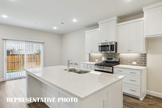 kitchen with visible vents, wood finished floors, tasteful backsplash, a sink, and appliances with stainless steel finishes