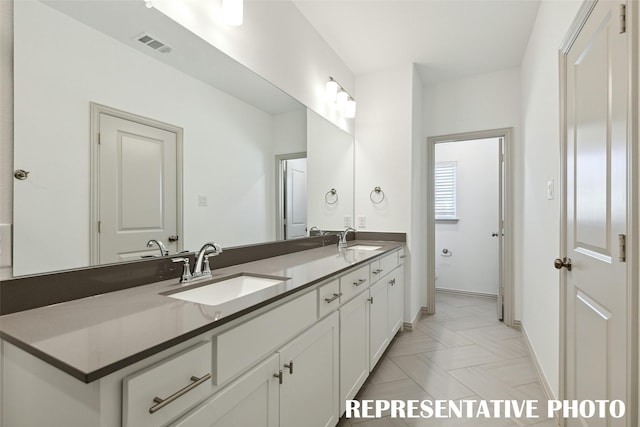 full bath featuring double vanity, baseboards, visible vents, and a sink