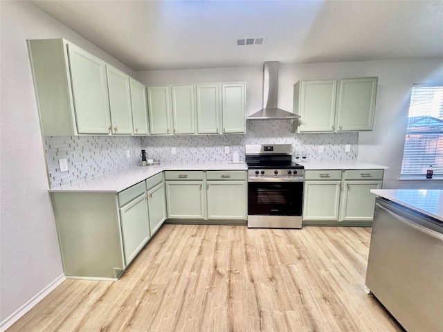 kitchen with visible vents, light wood-style flooring, wall chimney range hood, and stainless steel appliances