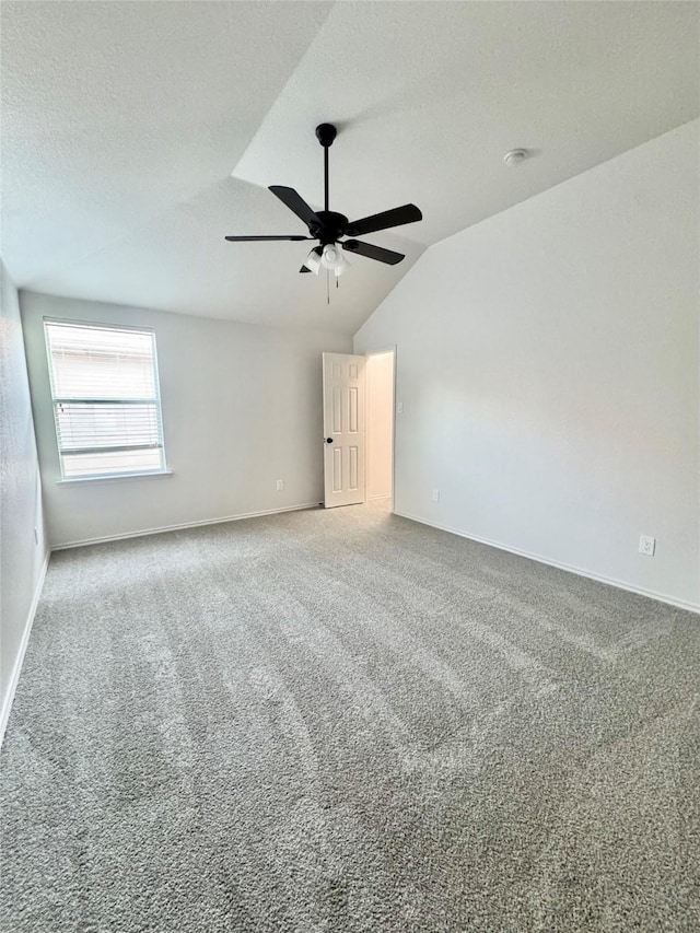 carpeted spare room featuring baseboards, ceiling fan, vaulted ceiling, and a textured ceiling